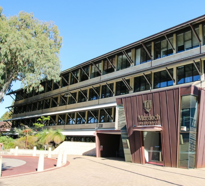Murdoch University campus building with its bronze-clad entrance, the university name above the doors and native landscaping in front